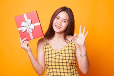Genç Asyalı kadın Sarı zemin üzerine bir hediye kutusu ile Tamam göster