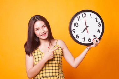 Sarı arka plan üzerinde bir saat noktasına genç Asyalı kadın