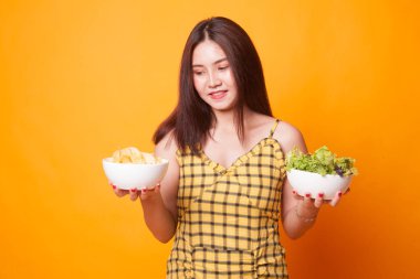 Patates kızartması ve salata sarı zemin üzerine genç Asyalı kadın