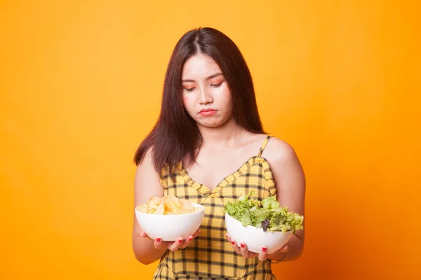 Junge Asiatin Mit Kartoffelchips Und Salat Auf Gelbem Hintergrund — Stockfoto