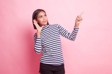 Heyecanlı Asyalı kadın pembe arka plandaki boşluğu işaret ediyor