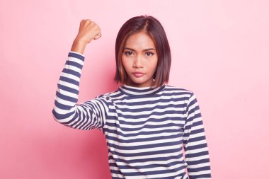 Başarılı genç Asyalı kadın pembe arka planda yumruğunu kaldır.