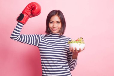 Genç Asyalı kadın boks eldiven ve pembe bir arka plan üzerinde salata ile