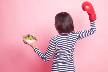 Genç Asyalı kadın boks eldiven ve pembe bir arka plan üzerinde salata ile