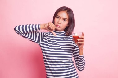 Genç Asyalı kadın başparmak aşağı nefret domates suyu pembe bir arka plan üzerinde