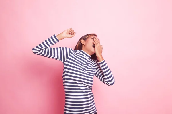 Sleepy young Asian woman yawn on pink background