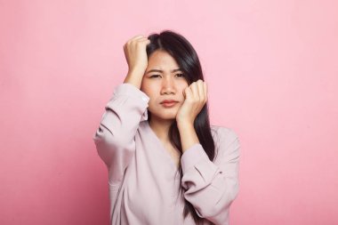 Genç Asyalı kadın hastalandı ve pembe arka planda başı ağrıdı.