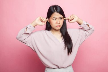 Genç Asyalı kadın her iki kulak parmak pembe bir arka plan üzerinde engellemek