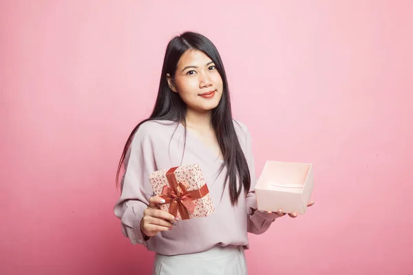 若いアジアの女性はピンクの背景に黄金のギフトボックスを開きます — ストック写真