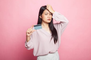 Genç Asyalı kadın baş ağrısı ve pembe arka planda boş bir kart.