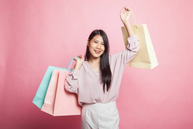 Genç Asyalı kadın pembe arka planda alışveriş çantasıyla mutlu.
