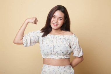 Güzel genç Asyalı kadın bej arka planda kaslarını esnetiyor.