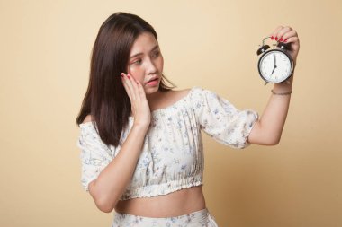 Genç Asyalı kadın bej arka planda bir saatle stresli