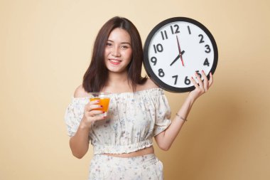 Bej renkli arka plan üzerinde bir saat içki portakal suyuyla Asyalı kadın