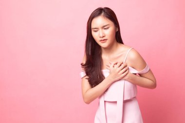 Genç Asyalı kadın göğüs ağrısı, pembe arka plan var