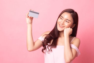 Genç Asyalı kadın pembe arka planda boş bir kartla düşünüyor.