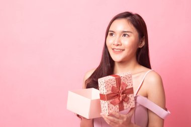 Pembe arka planda hediye kutusu olan genç bir Asyalı kadın.