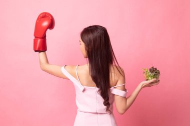 Pembe arka planda saati ve salatası olan genç Asyalı kadın.