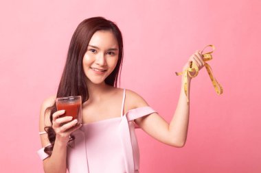 Domates suyu ve pembe bir arka plan üzerinde ölçüm bandı ile genç Asyalı kadın