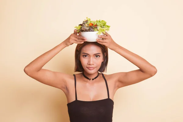 Healthy Asian woman with salad on beige background