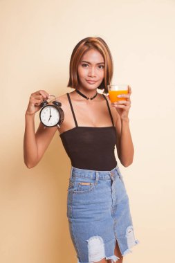Bej renkli arka plan üzerinde bir saat içki portakal suyuyla Asyalı kadın