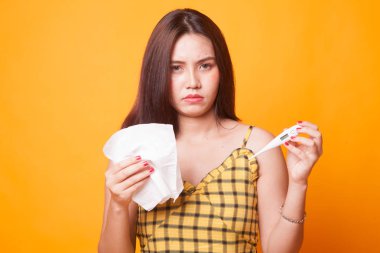 Genç Asyalı kadın hasta ve grip üzerinde sarı arka plan var