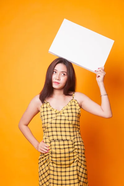 黄色の背景の白い空白記号を持つ若いアジア女性 — ストック写真