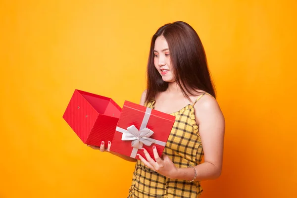 年轻的亚洲妇女打开一个礼物盒在黄色背景 — 图库照片