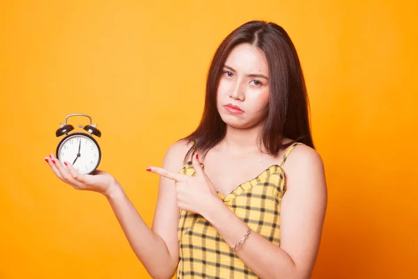 愤怒的年轻亚洲妇女指向一个时钟在黄色背景 — 图库照片