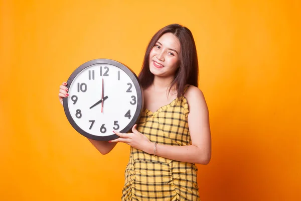年轻的亚洲妇女与时钟在黄色背景 — 图库照片