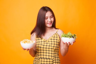 Patates kızartması ve salata sarı zemin üzerine genç Asyalı kadın