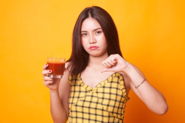 Genç Asyalı kadın başparmak aşağı nefret domates suyu Sarı zemin üzerine