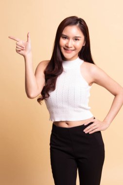 Genç Asyalı kadın gülümsüyor ve bej arka planda nokta.