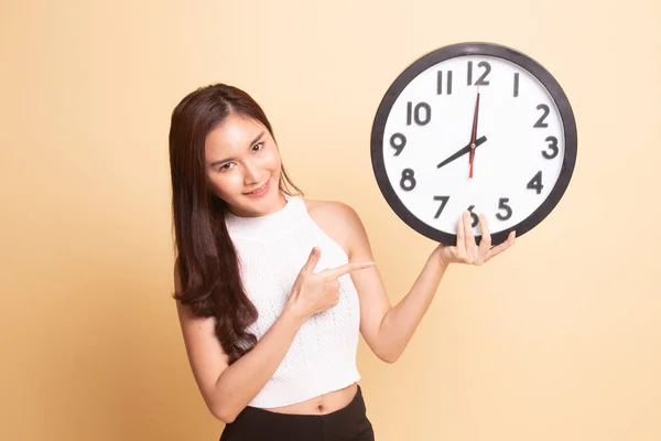 Junge Asiatin Zeigt Auf Eine Uhr Auf Beigem Hintergrund — Stockfoto