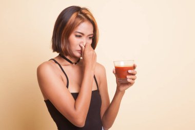 Genç Asyalı kadın bej arka planda domates suyundan nefret eder.