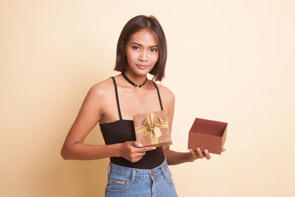 Молодая Азиатка Открывает Золотую Подарочную Коробку Бежевом Фоне — стоковое фото
