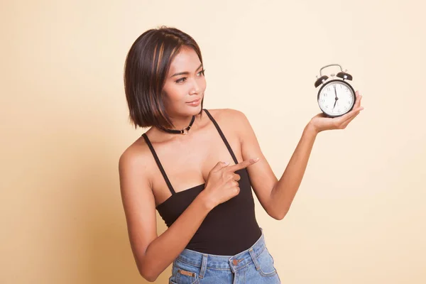 若いですアジアの女性は ベージュの背景に時計を指す — ストック写真