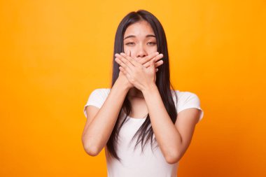 Güzel genç Asyalı kadın parlak sarı zemin üzerine ağzını kapatın