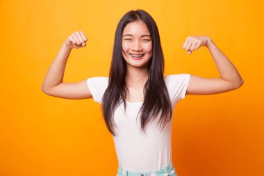 Güzel genç Asyalı kadın flex pazı parlak sarı zemin üzerine