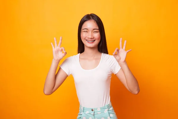 アジアの女性ダブル 手の記号を表示して 明るい黄色の背景に笑顔 — ストック写真