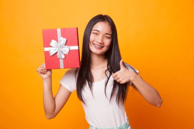 Genç Asyalı kadın başparmak yukarıya ile parlak sarı zemin üzerine bir hediye kutusu