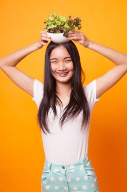 Parlak sarı zemin üzerine salata sağlıklı Asyalı kadın