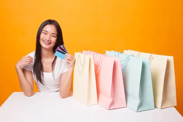 Junge Asiatin Mit Einkaufstasche Und Blankokarte Auf Leuchtend Gelbem Hintergrund — Stockfoto