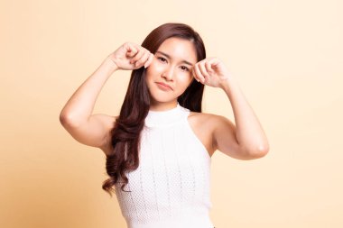 Genç Asyalı kadın bej arka planda üzgün ve ağlıyor