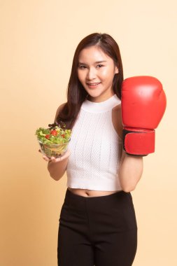 Genç Asyalı kadın ile boks eldiven ve salata bej renkli arka plan üzerinde
