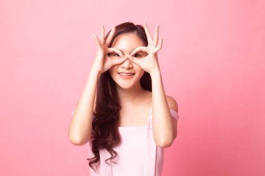 Asyalı kadın yapmak komik Çift Ok işareti olarak pembe bir arka plan üzerinde gözlük