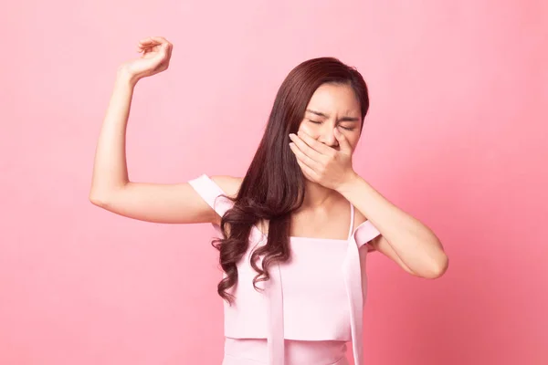 Sleepy young Asian woman yawn on pink background