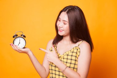 Sarı arka plan üzerinde bir saat noktasına genç Asyalı kadın