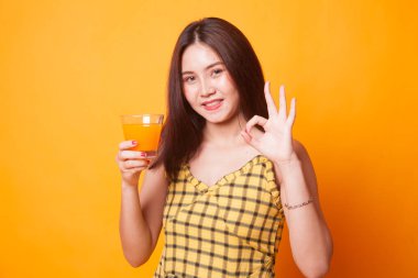 Portakal suyu gösteri genç Asyalı kadın içki Tamam işareti üzerinde sarı arka plan