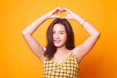Genç Asyalı kadın kalp el işareti Sarı zemin üzerine el hareketi